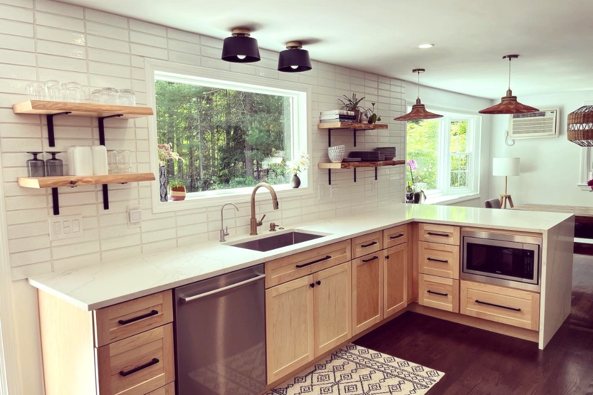 Base cabinet only sink wall with natural wood shaker cabinets, white countertops, white stacked subway tile backsplash, and boho-style floating shelves and woven light fixtures