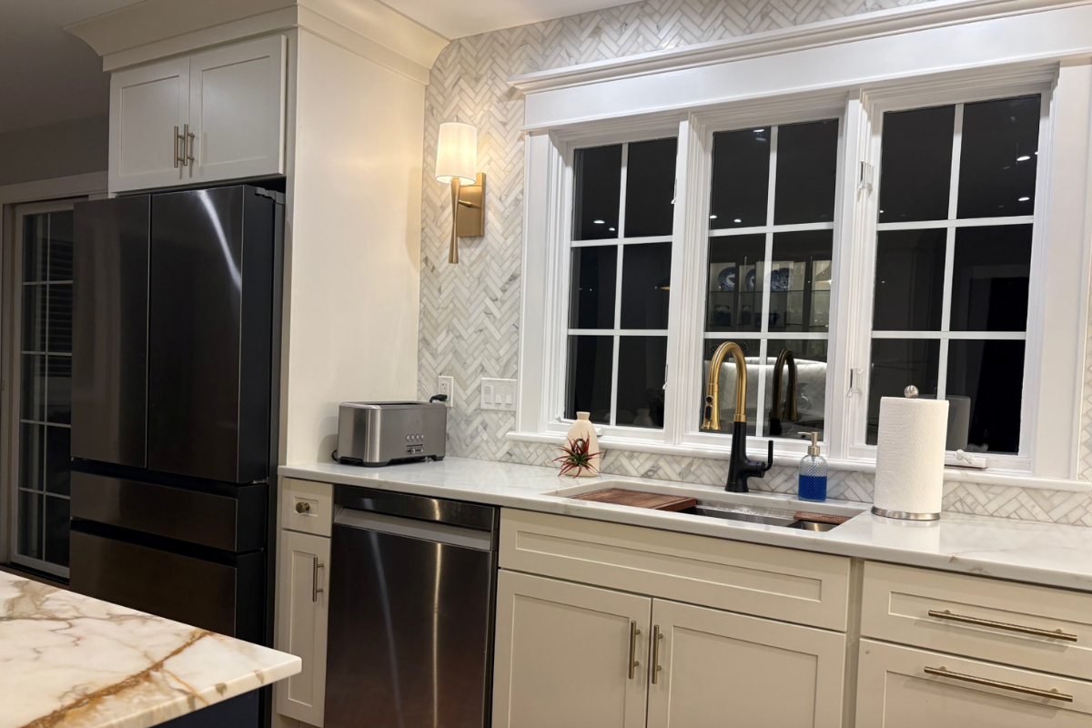 Large L-shaped white shaker kitchen design with a long navy island and white stone countertops