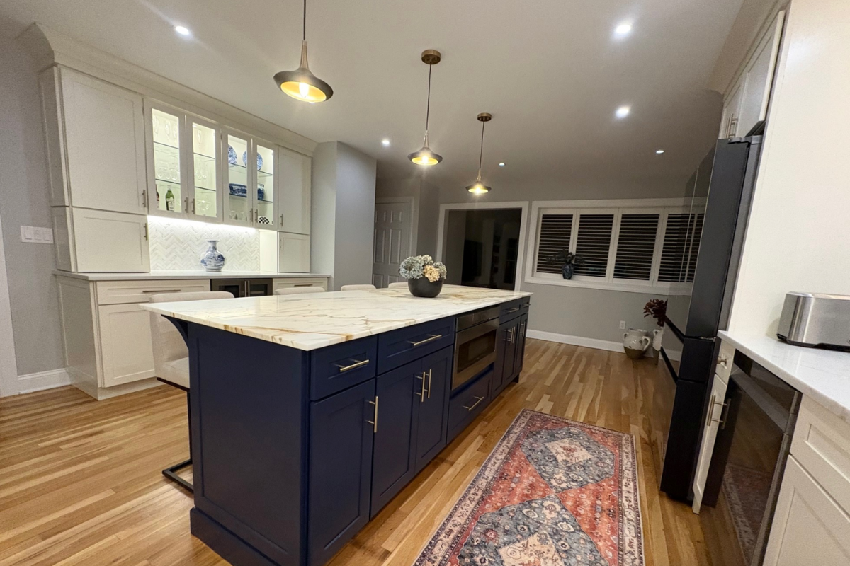 Large L-shaped white shaker kitchen design with a long navy island and white stone countertops