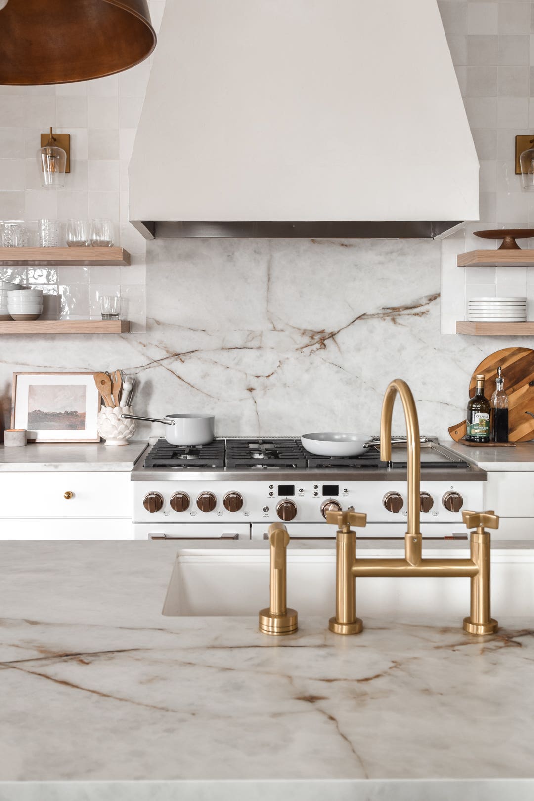 White shaker kitchen cabinets with marble countertops and white range hood