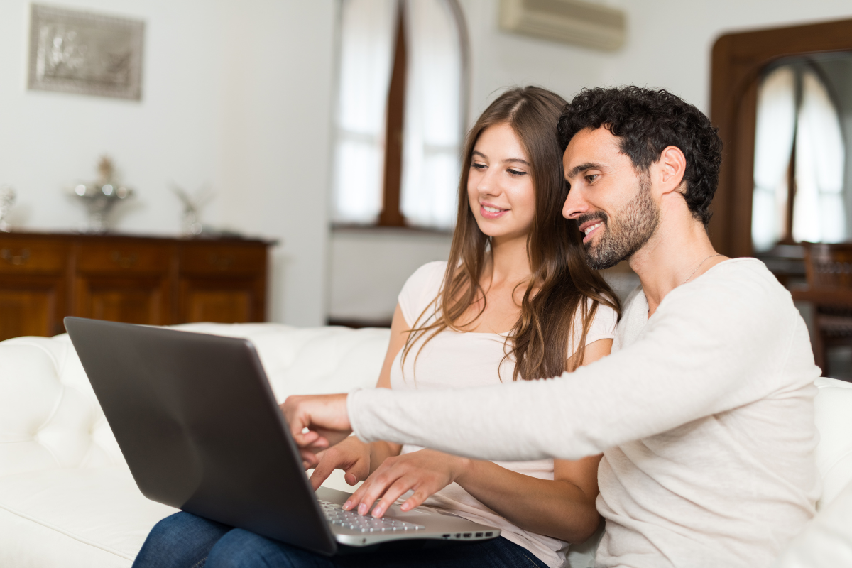 Couple shopping online in their living room Couple shopping online in their living room