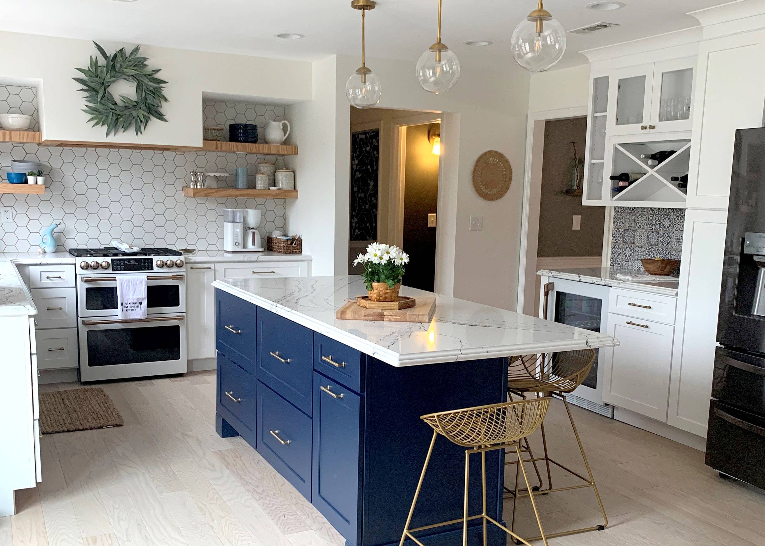 Farmhouse style white shaker kitchen cabinets and navy blue island with gold hardware