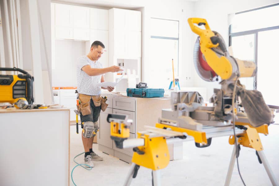 Contractor installing white shaker kitchen cabinets with yellow power tools