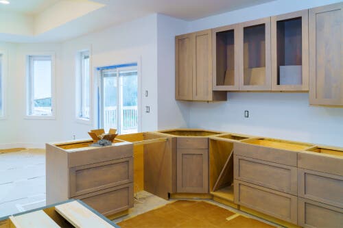 Light wood kitchen cabinets Light wood kitchen cabinets being installed in large white room