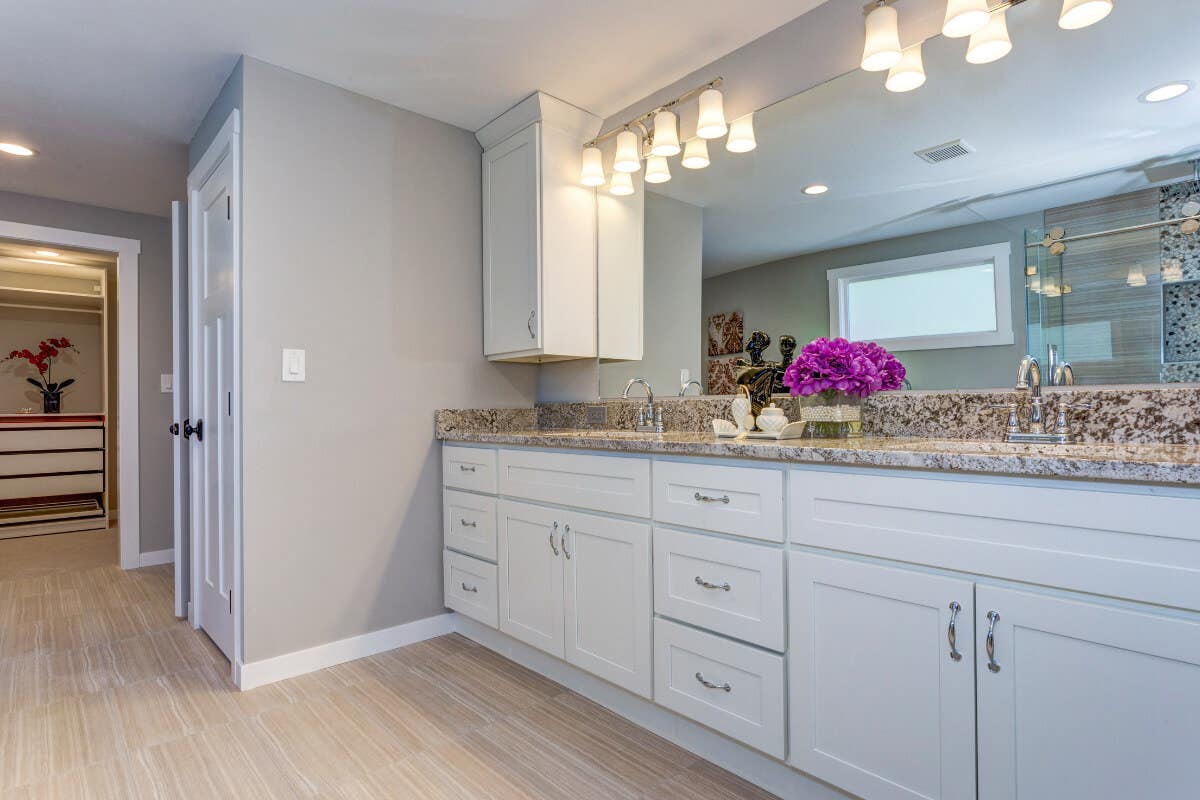 Long double vanity in white shaker door style with brown stone countertops Long double vanity in white shaker door style