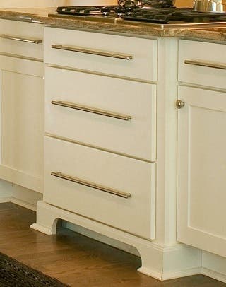 cream-colored cabinet drawer unit bumped out with furniture-look feet supports cooktop cream-colored cabinet drawer unit bumped out with furniture-look feet supports cooktop