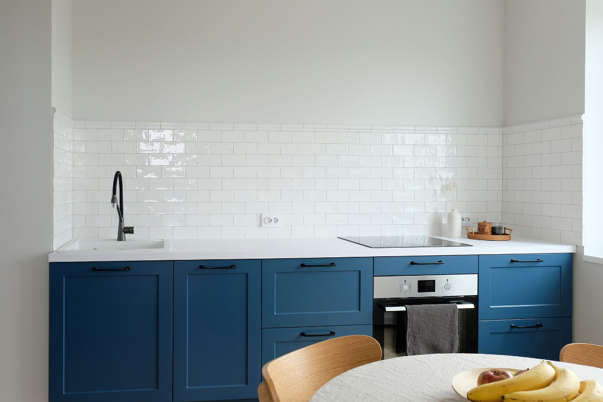 Navy blue shaker base kitchen cabinets only with white countertop and white subway backsplash