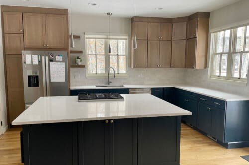 Newport Fossil and Indigo kitchen cabinets Contemporary L-shaped kitchen design with light beige kitchen cabinets above and dark blue base and island cabinets with white countertops