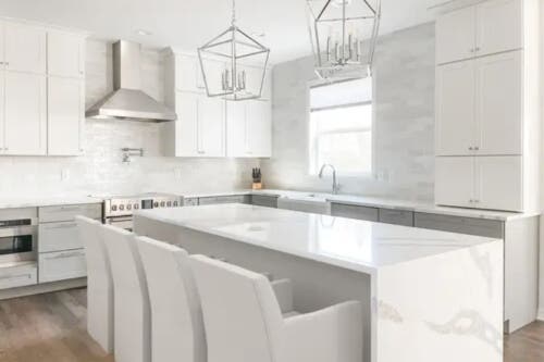 Newport Lily and Fog kitchen cabinets Large L-shaped white shaker style cabinet design with stacked cabinets, gray painted island and marble-like quartz countertops