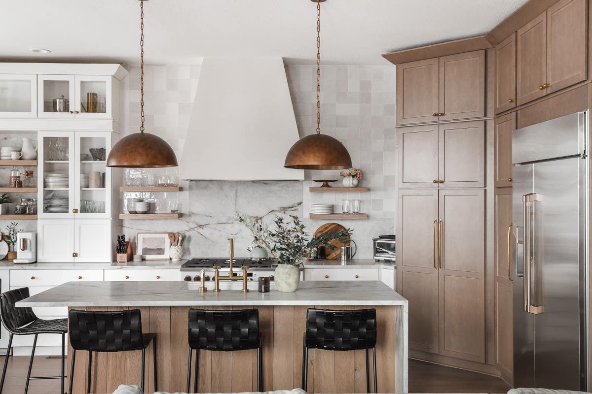 White and light brown stained shaker cabinets with cream colored stone countertops and slab backsplash