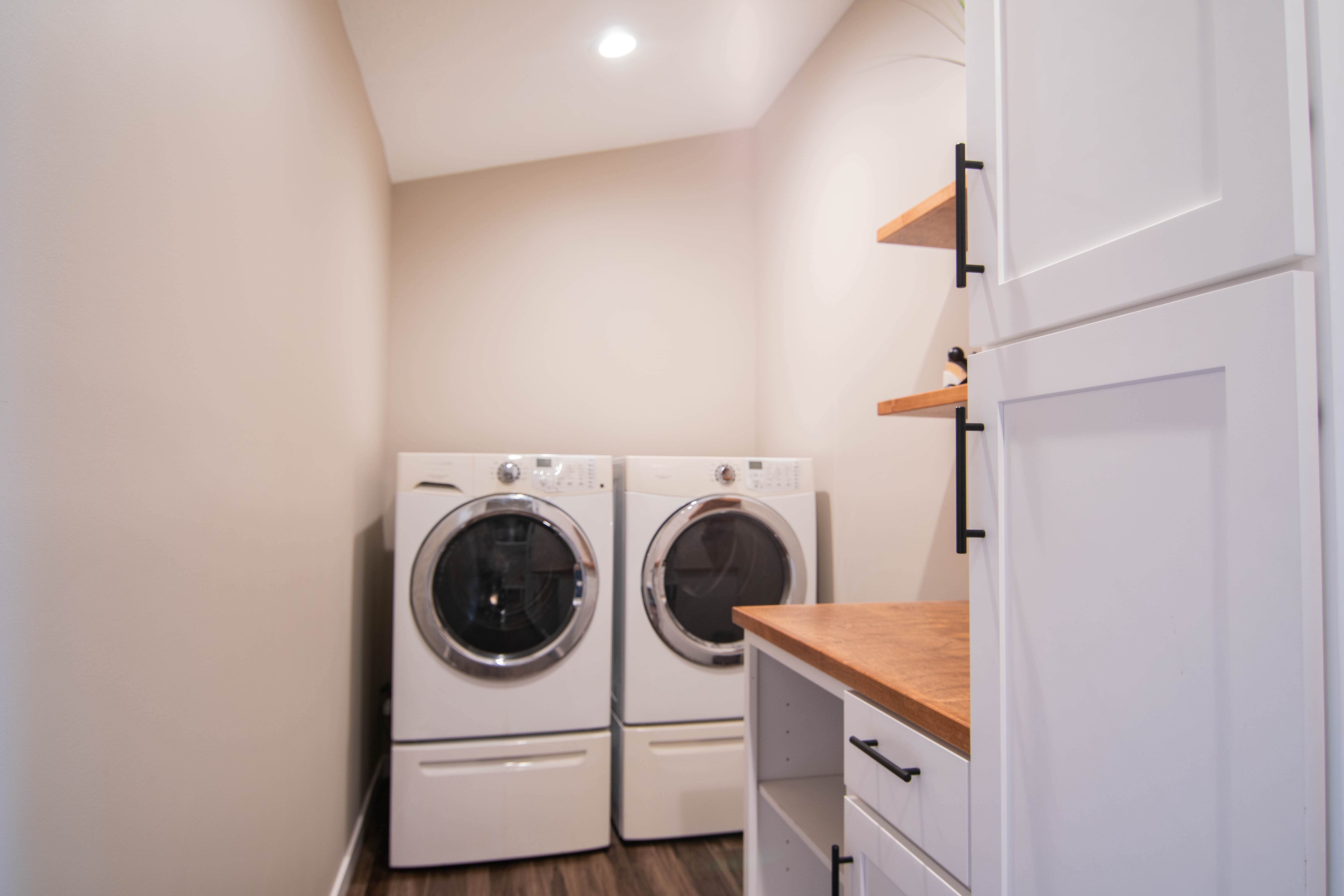 CliqStudios project: White laundry and mudroom cabinets with warm golden wood floating shelves