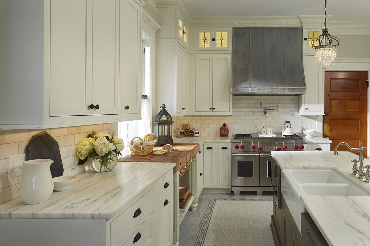 Large decorative L-shaped kitchen with inset white shaker kitchen cabinets, army green island, and white marble countertops