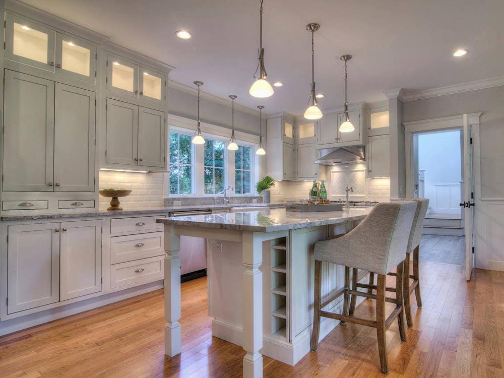 Country kitchen design includes timeless white inset cabinets with exposed hinge barrels, square turned spindle island legs, and wine storage built in to the island.