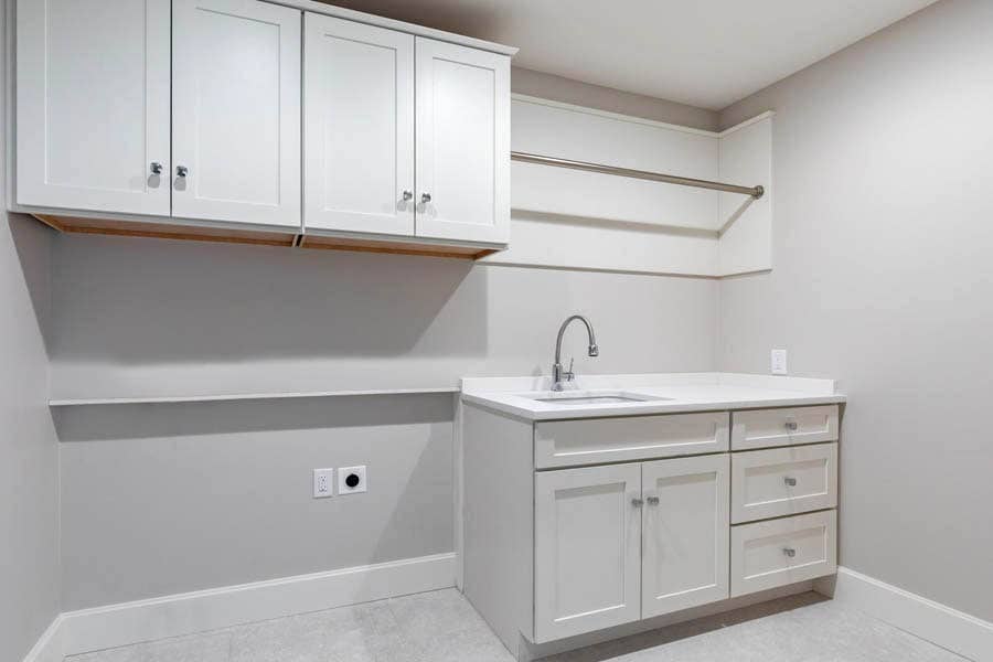 white laundry room with Shaker cabinets, sink and drying rack