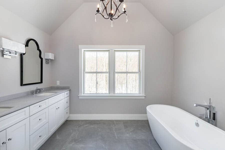 large master bathroom with double vanity, vaulted ceiling with chandelier and free-standing tub