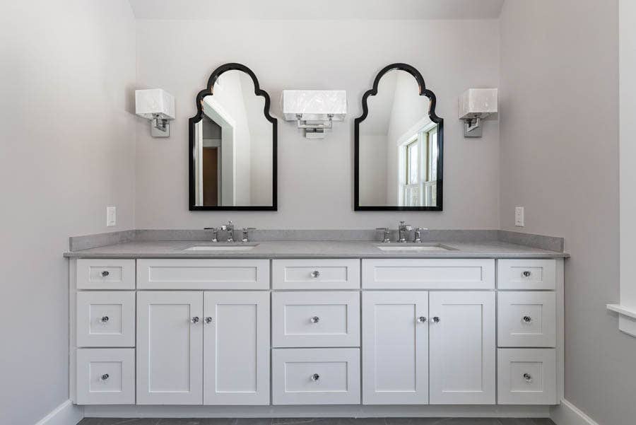 double vanity with white Shaker cabinets, gray countertop with two black beveled mirrors above