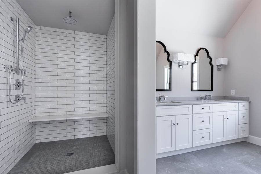 walk in shower with white subway tile and double vanity separated by a wall