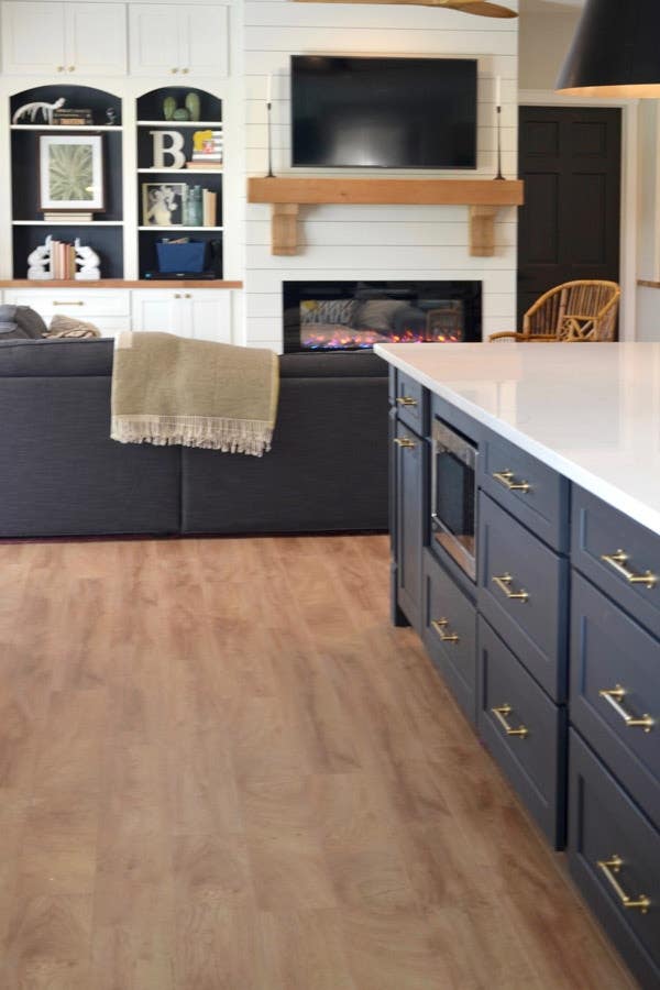 CliqStudios Shaker cabinets in Black used in an island with a white countertop. Behind that is a sitting area using CliqStudios Shaker cabinets in white for storage. CliqStudios Shaker cabinets in Black used in an island with a white countertop. Behind that is a sitting area using CliqStudios Shaker cabinets in white for storage.
