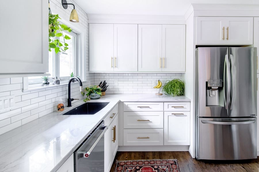 A kitchen using CliqStudios Shaker cabinets in White, with stainless steel appliances and green plant accent pieces.