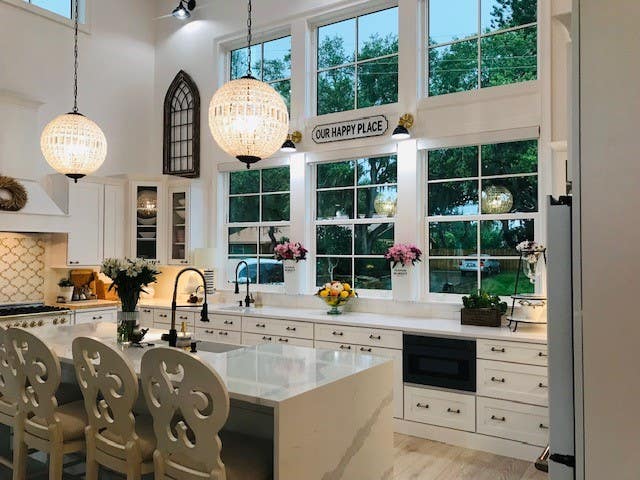White shaker cabinet kitchen with large mullion windows over sink, custom wood hood, and large island with waterfall quartz countertop White shaker cabinet kitchen with large mullion windows over sink, custom wood hood, and large island with waterfall quartz countertop