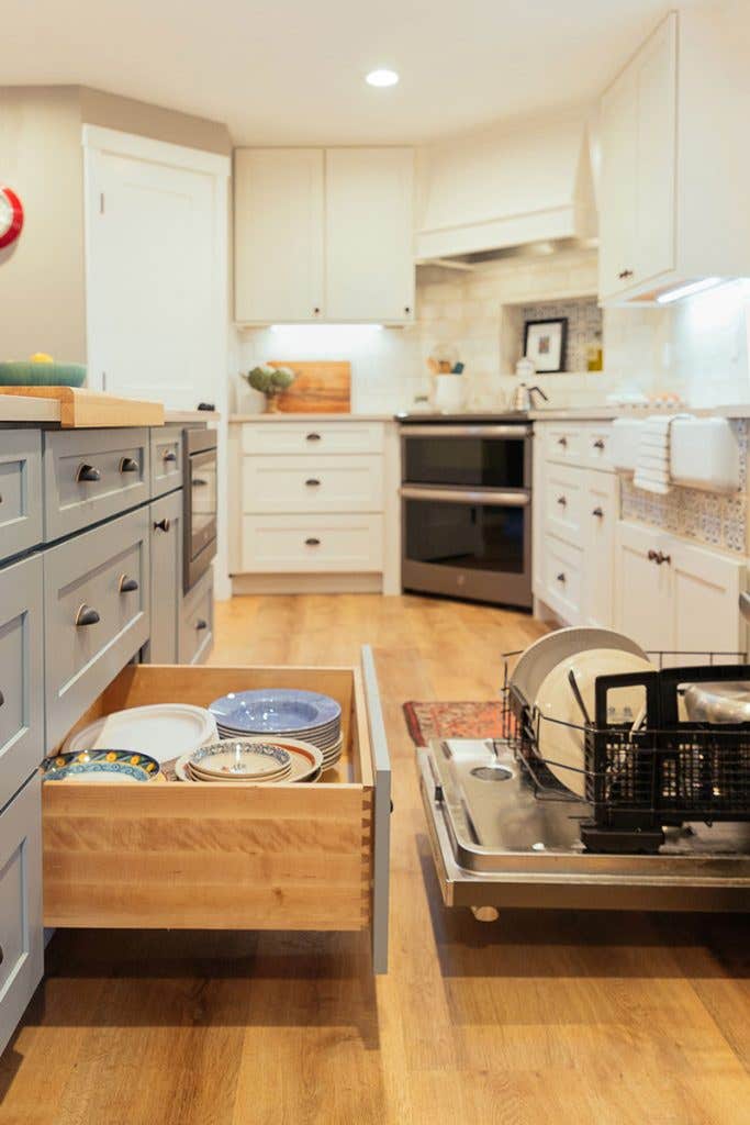 Open dishwasher and dish storage door open in white and blue kitchen Open dishwasher and dish storage door open in white and blue kitchen