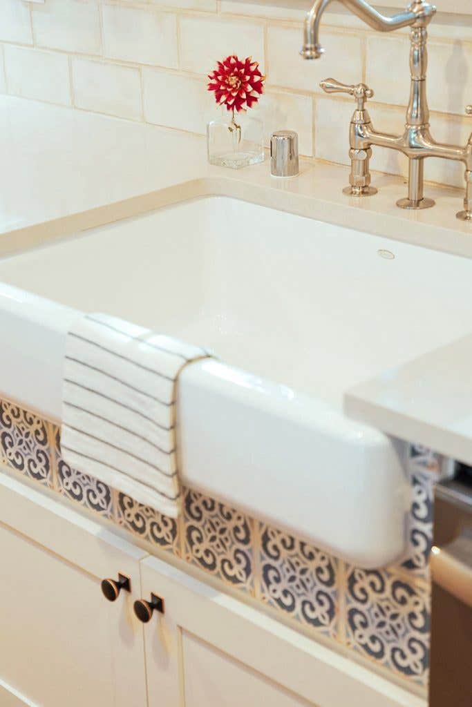 White apron sink with blue tile detail below the front skirt White apron sink with blue tile detail below the front skirt