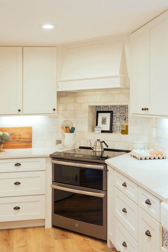 Stainless steel range in the corner of a kitchen with white cabinets and range hood Stainless steel range in the corner of a kitchen with white cabinets and range hood