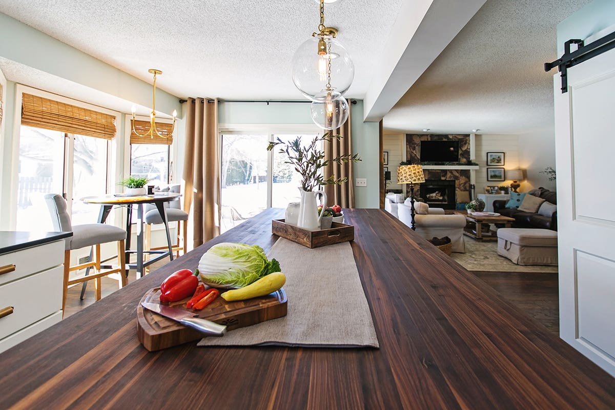 White slab style kitchen cabinets, gold hardware, and large island with dark walnut butcher block countertop