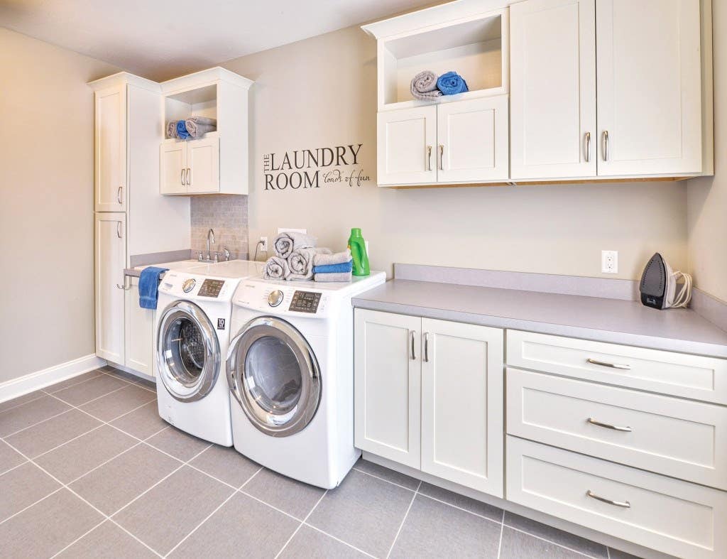 Spacious and bright laundry room custom built with CliqStudios.com shaker style cabinets. Shown Shaker cabinet style in painted White finish.