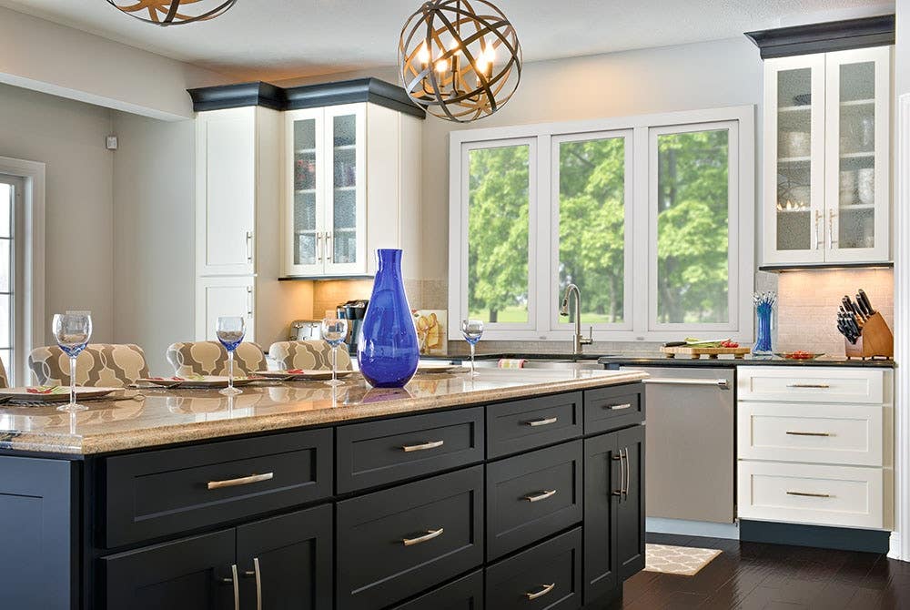 Beautifully designed open floor plan kitchen features painted shaker style cabinetry by CliqStudios. Shown Shaker cabinet style in painted White finish and paired with Shaker in painted Black finish.