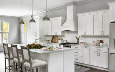 Open kitchen with white shaker cabinets, large island, white wood range hood with holiday decorations
