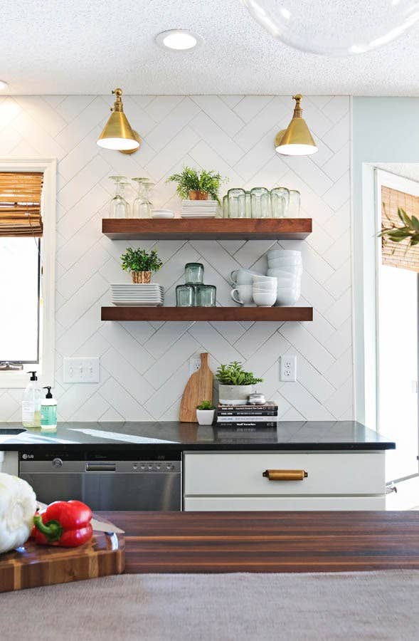 White shaker kitchen cabinets with dark wood butcher block and floating shelves