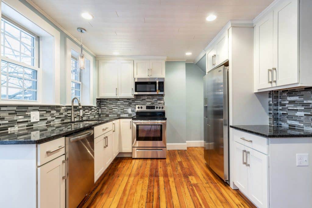 small u-shaped kitchen with white cabinets, light blue walls, black countertops and original wood floors small u-shaped kitchen with white cabinets, light blue walls, black countertops and original wood floors