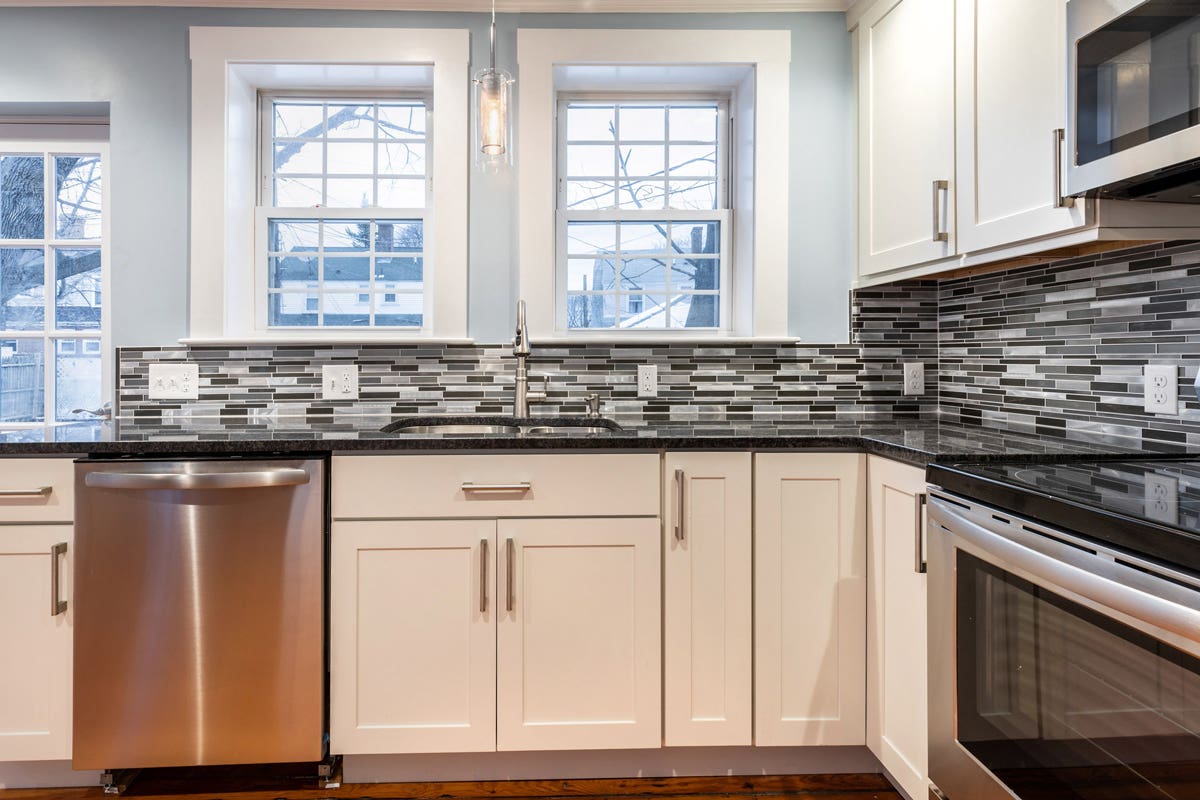 White shaker kitchen cabinets with mullion windows over the sink and a stainless range and microwave on the right White shaker kitchen cabinets with mullion windows over the sink and a stainless range and microwave on the right