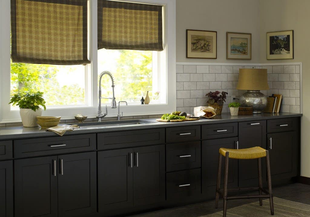 kitchen wall with black shaker cabinets, gray marble backsplash and countertops and stainless bar pulls and faucet