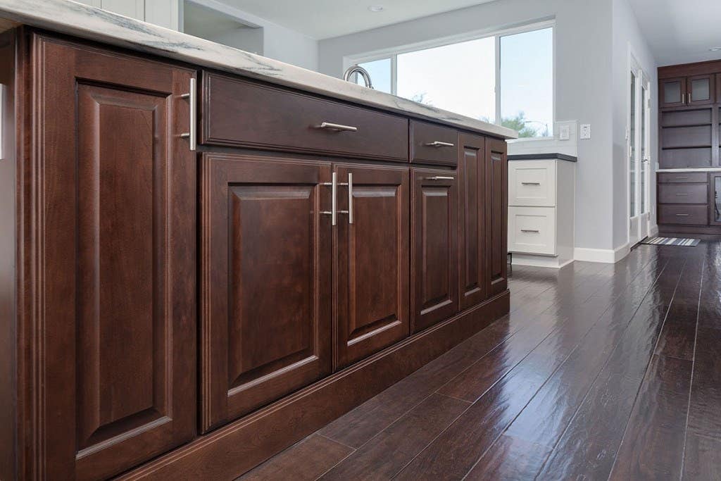 cherry cabinets with raised panel doors are used to build a kitchen center island trimmed with ogee toekick for a furniture look