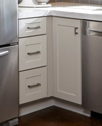 Stainless Steel Pulls Cabinet Hardware closeup of white shaker cabinets in corner showing spacer by the drawer base and door-only cabinet used to allow cabinets to open freely past projecting bar pulls