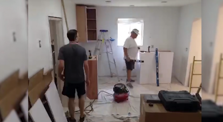 Contractors working in an empty room with tools installing kitchen cabinetry Contractors working in an empty room with tools installing kitchen cabinetry