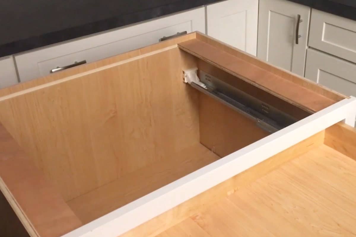 White drawer glide brackets at the back of a cabinet drawer