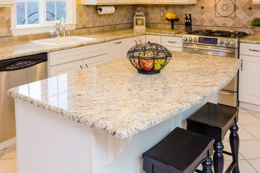 Gaillo Ornamental granite countertops White raised panel kitchen design with cream, gold, and brown speckled granite countertops.