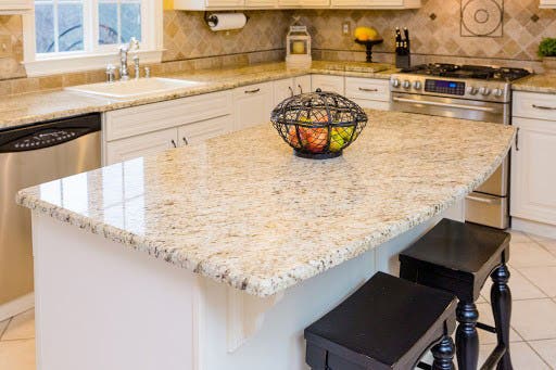 White raised panel kitchen design with cream, gold, and brown speckled granite countertops.