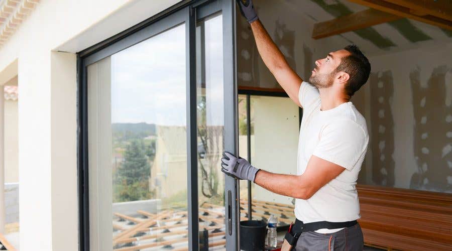 Young window installer in white t-shirt putting in a door while remodeling a house Young window installer in white t-shirt putting in a door while remodeling a house