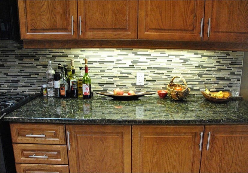 Pomodoro granite countertops Raised panel cherry wood base cabinets with brushed nickel pulls and a green patterned granite countertop.