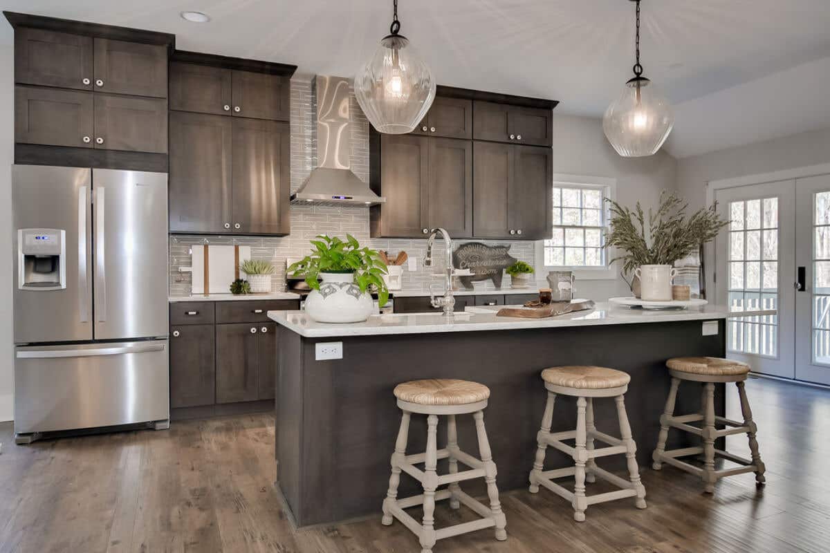 Dark brown shaker kitchen design with stacked cabinets, a kitchen island and cream-colored quartz countertops