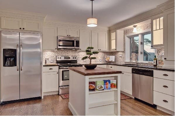 White shaker cabinets in kitchen have stacked crown molding to meet ceiling