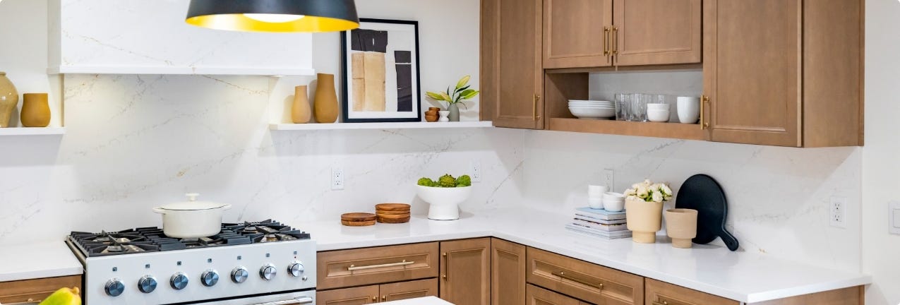 Lenox Fossil kitchen cabinets Decorative recessed door style in light wood finish with gold bar pulls and white quartz countertops