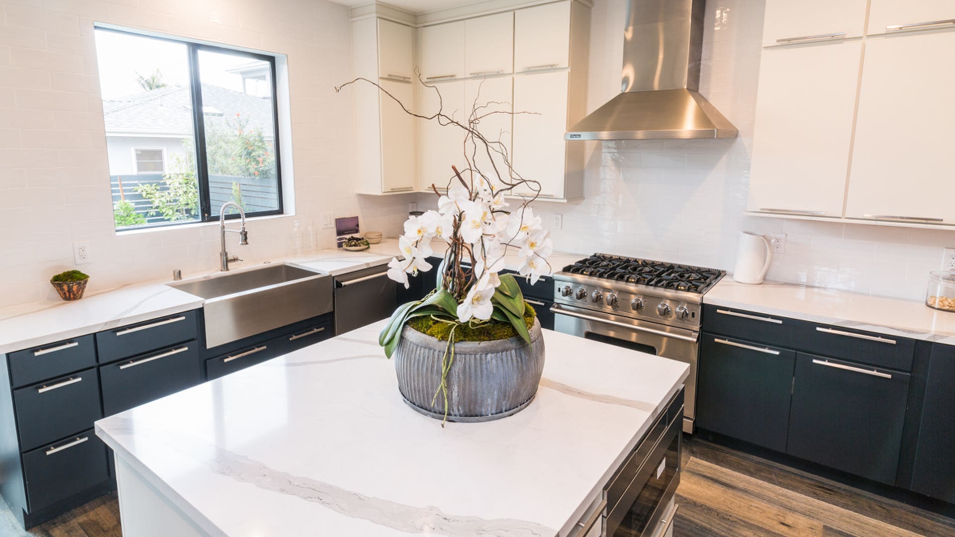 L-shaped slab door style kitchen and island with white wall cabinets, black base, and island cabinets, with nickel bar pulls L-shaped slab door style kitchen and island with white wall cabinets, black base, and island cabinets, with nickel bar pulls