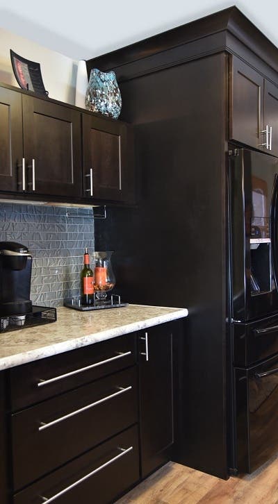 Custom beverage station built of black stained birch shaker cabinets has extra height above the counter to allow access to the coffee maker, and above-cabinet display space for glass art