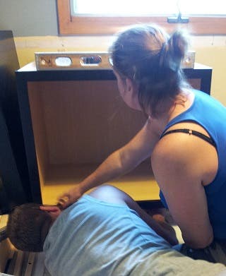 Designer Tessa and husband Jake work together, leveling a base cabinet in their kitchen Designer Tessa and husband Jake work together, leveling a base cabinet in their kitchen