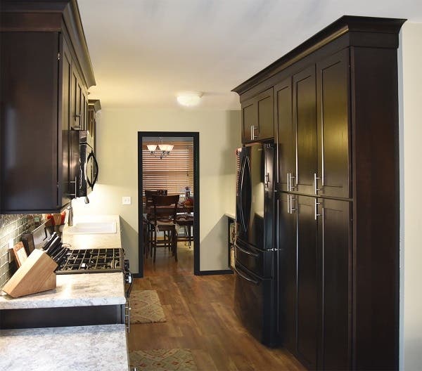 galley kitchen has wood-look vinyl tile floor, ebony cabinets in a shaker style, glass backsplash and granite-look laminate countertop galley kitchen has wood-look vinyl tile floor, ebony cabinets in a shaker style, glass backsplash and granite-look laminate countertop